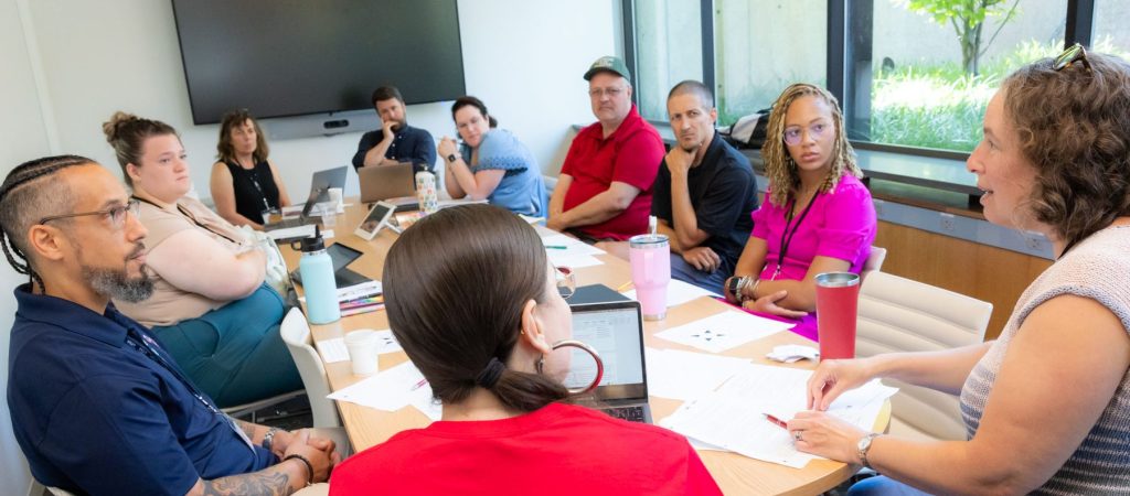 People around a table listening to an instructor
