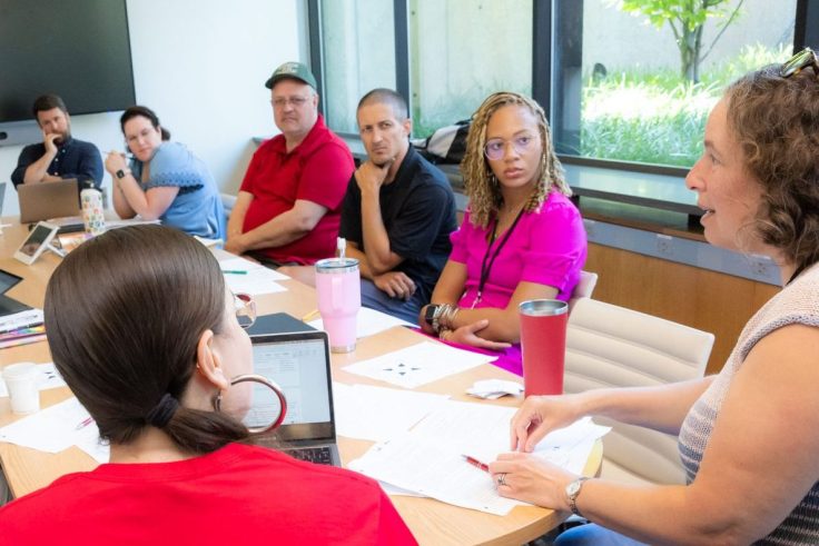 People around a table listening to an instructor