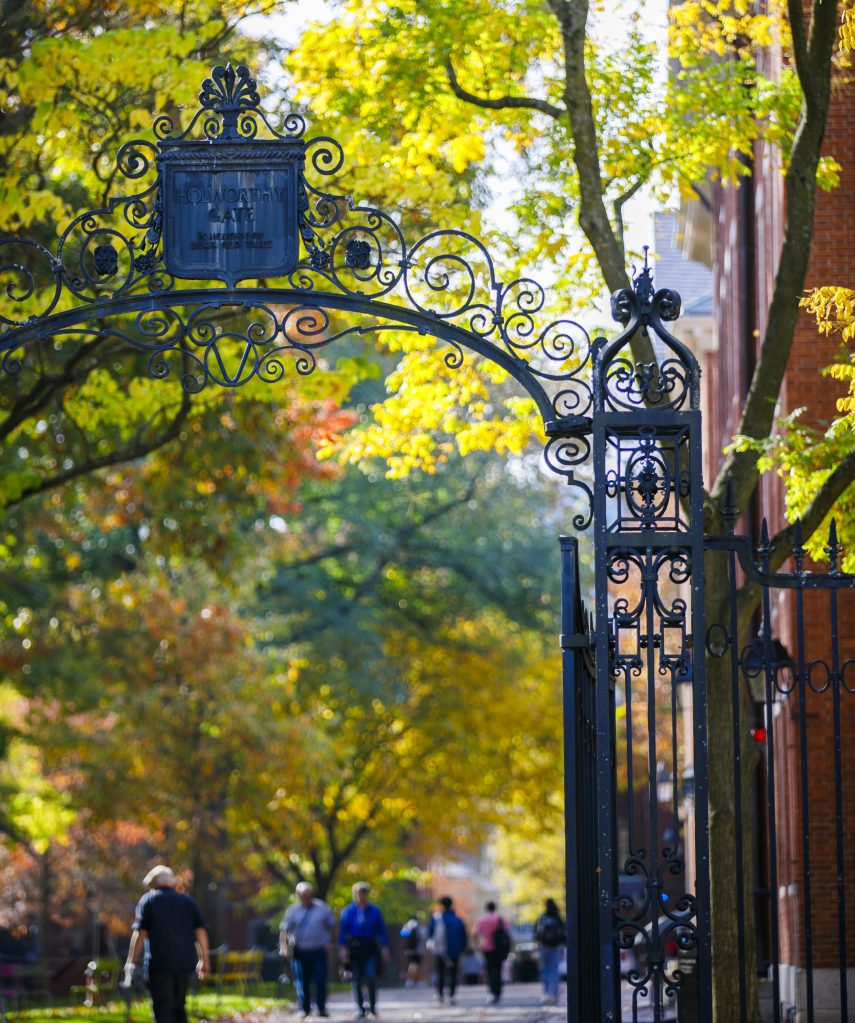 A view of people walking outside in autumn under an arched gate