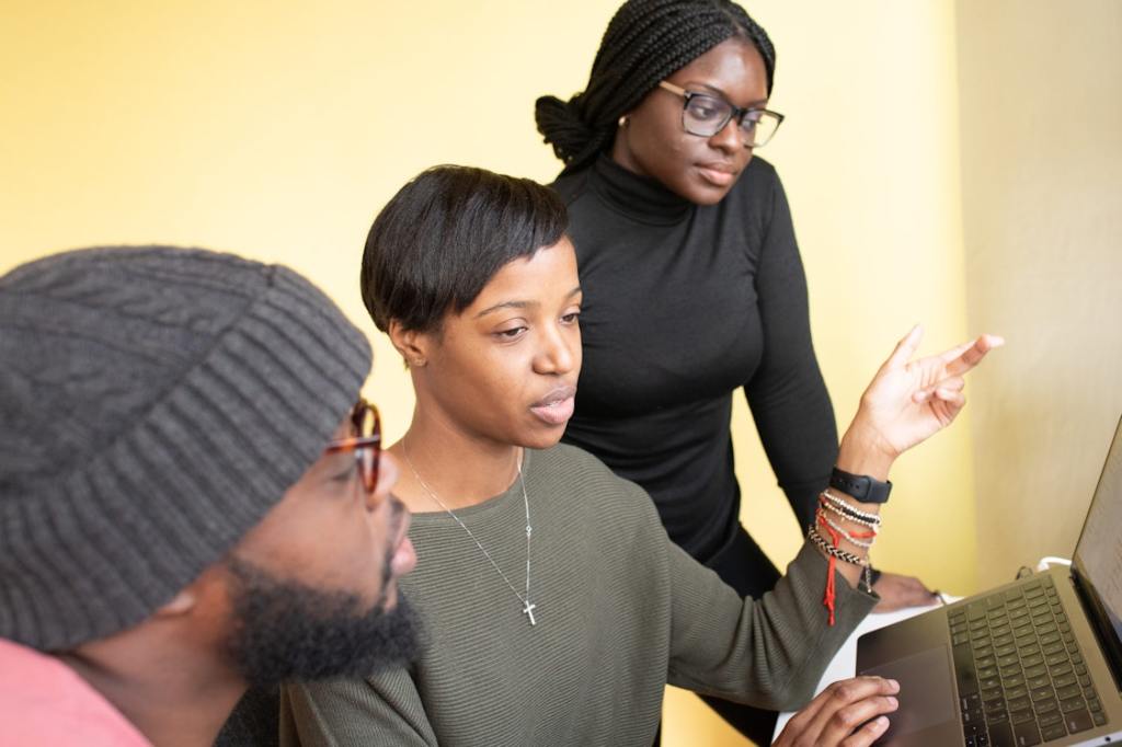 Three people in discussion looking at a laptop